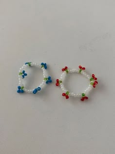 two beaded bracelets sitting next to each other on a white surface with red, blue and green beads