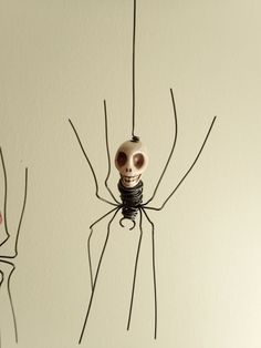 two spider sculptures hanging from strings in the shape of skulls