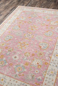 a pink and yellow area rug on a wooden floor with wood floors in the background