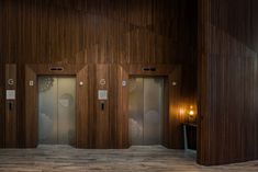 an empty room with wooden walls and two doors that are open to the public restroom