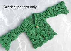 a green crocheted sweater laying on top of a white surface