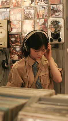 a woman wearing headphones and listening to music in a recording studio with records on the wall