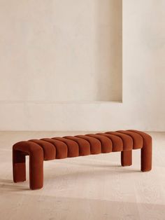 an orange bench sitting on top of a hard wood floor next to a white wall