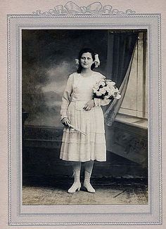 an old black and white photo of a woman holding flowers