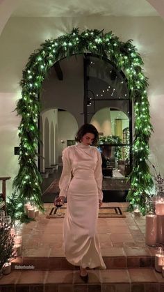 a woman in a white dress is standing on steps with candles and wreaths around her