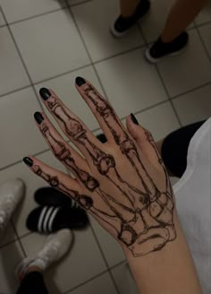 a woman's hand with black and white tattoos on it, in front of a tiled floor