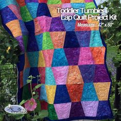 a colorful quilt is hanging on a tree branch with the words toddler tumbler lap quilt project kit