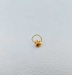 a gold ring with a single flower on it's side sitting on a white surface