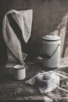 a white canister sitting on top of a wooden table next to a tea towel