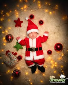 a baby dressed as santa clause laying next to christmas decorations