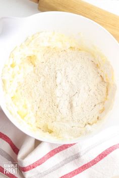 a white bowl filled with batter sitting on top of a red and white striped towel