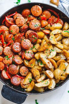 a skillet filled with potatoes and sausages, garnished with parsley