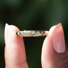 a woman's hand holding a gold ring with three diamonds on the inside of it