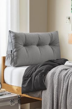 a bed with a gray comforter on top of it next to a white wall