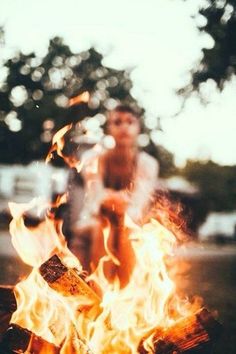 a person standing in front of a fire with flames coming out of it and on the ground