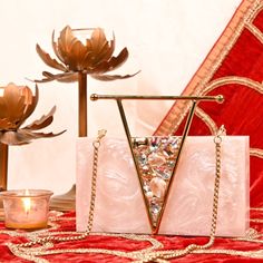 a white purse sitting on top of a table next to a candle and flower vase