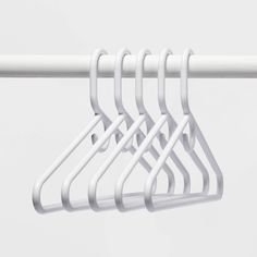 four white clothes hangers hanging on a rail