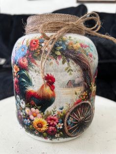 a painted glass jar with a rooster and flowers on it