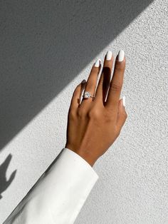 a woman's hand with white manicured nails and ring