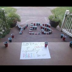 a sign that is on the ground with cups in front of it and some plants behind it