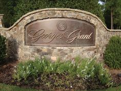 a sign that says george grant in front of some bushes and trees on the other side