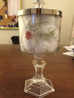 a glass container with writing on it sitting on top of a wooden table next to a wall