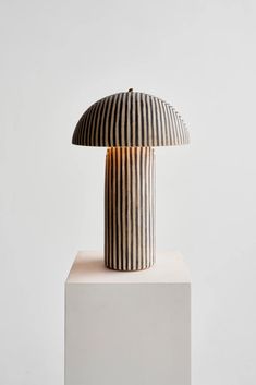 a striped lamp sitting on top of a white pedestal