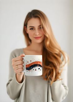 a woman holding up a coffee mug with an orange and black wave on it's side