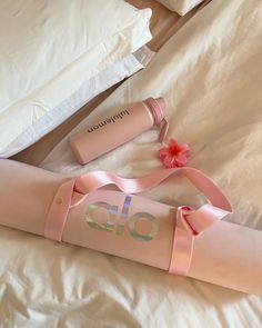 a pink umbrella laying on top of a white bed next to pillows and pillow cases