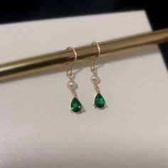 Introducing our stunning minimalist teardrop emerald gold and pearl drop earrings! Handcrafted with care and attention to detail, these earrings are the perfect blend of classic and modern style. The teardrop-shaped emerald gemstones are delicately set in 18k gold plated, giving these earrings an elegant and timeless look. The addition of the lustrous cultured pearls adds a touch of sophistication to these already stunning earrings. Measuring approximately 31mm in length, 5mm width, these earrin Elegant Teardrop May Birthstone Earrings, Classic Green Pearl Drop Earrings, Elegant Teardrop Earrings For May Birthstone, Elegant May Birthstone Teardrop Earrings, Green Elegant Pearl Drop Earrings, Elegant Green Drop Pearl Earrings, Elegant Green Pearl Drop Earrings, Elegant Teardrop Earrings For May Birthstone Gift, Elegant May Birthstone Dangle Teardrop Earrings