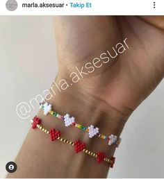 the hand is holding three bracelets with hearts and flowers on each one, while another wristband has been made out of beads