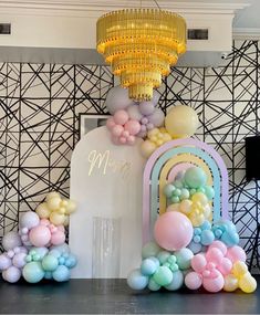 balloons and streamers are on display in front of a wall with a chandelier