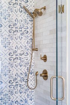 the shower head and handset of a modern bathroom with blue and white wallpaper