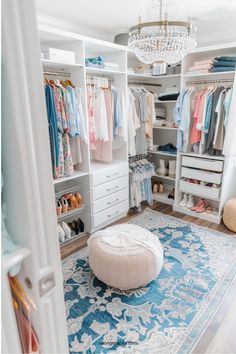 a white closet filled with lots of clothes and shoes next to a chandelier