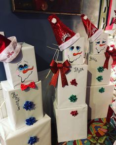 three snowmen made out of white boxes with red and blue bows on them, one is wearing a santa hat