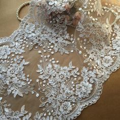 a white lace with flowers and pearls on it