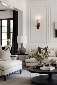 a living room filled with white furniture and black tables in front of two large windows