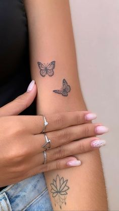 two women with tattoos on their arms and one has a butterfly tattoo on her arm