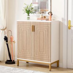 a white cabinet sitting next to a mirror on top of a wooden floor in front of a door