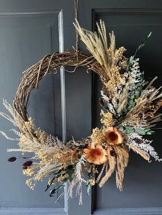 a wreath hanging on the front door with dried flowers and foliage in it, ready to be hung