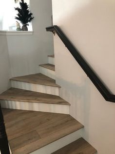 there is a black handrail on the stairs in this house with white walls and wood flooring