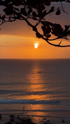 the sun is setting over the ocean as people are out in the water