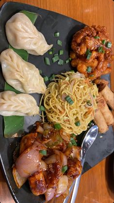 a plate with noodles, meat and vegetables on it next to other foods that are sitting on a table