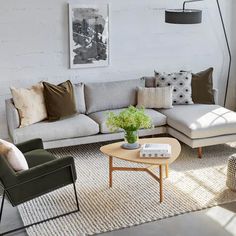 a living room with couches, chairs and a coffee table in front of a white brick wall