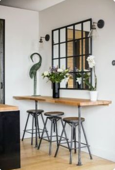 a dining table with four stools in front of it and a mirror on the wall