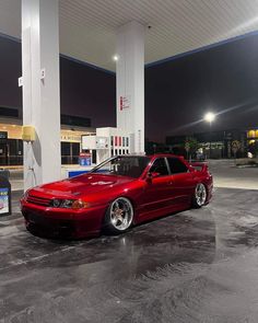 a red car parked in front of a gas station