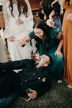 two people are laying on the ground and one person is holding a wine glass in his mouth