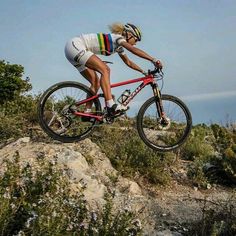 a woman riding a bike on top of a rocky hill