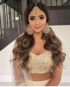 a woman with long hair wearing a white dress and gold jewelry is posing for the camera