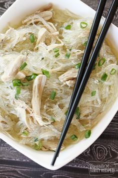 a bowl filled with chicken and noodles next to chopsticks